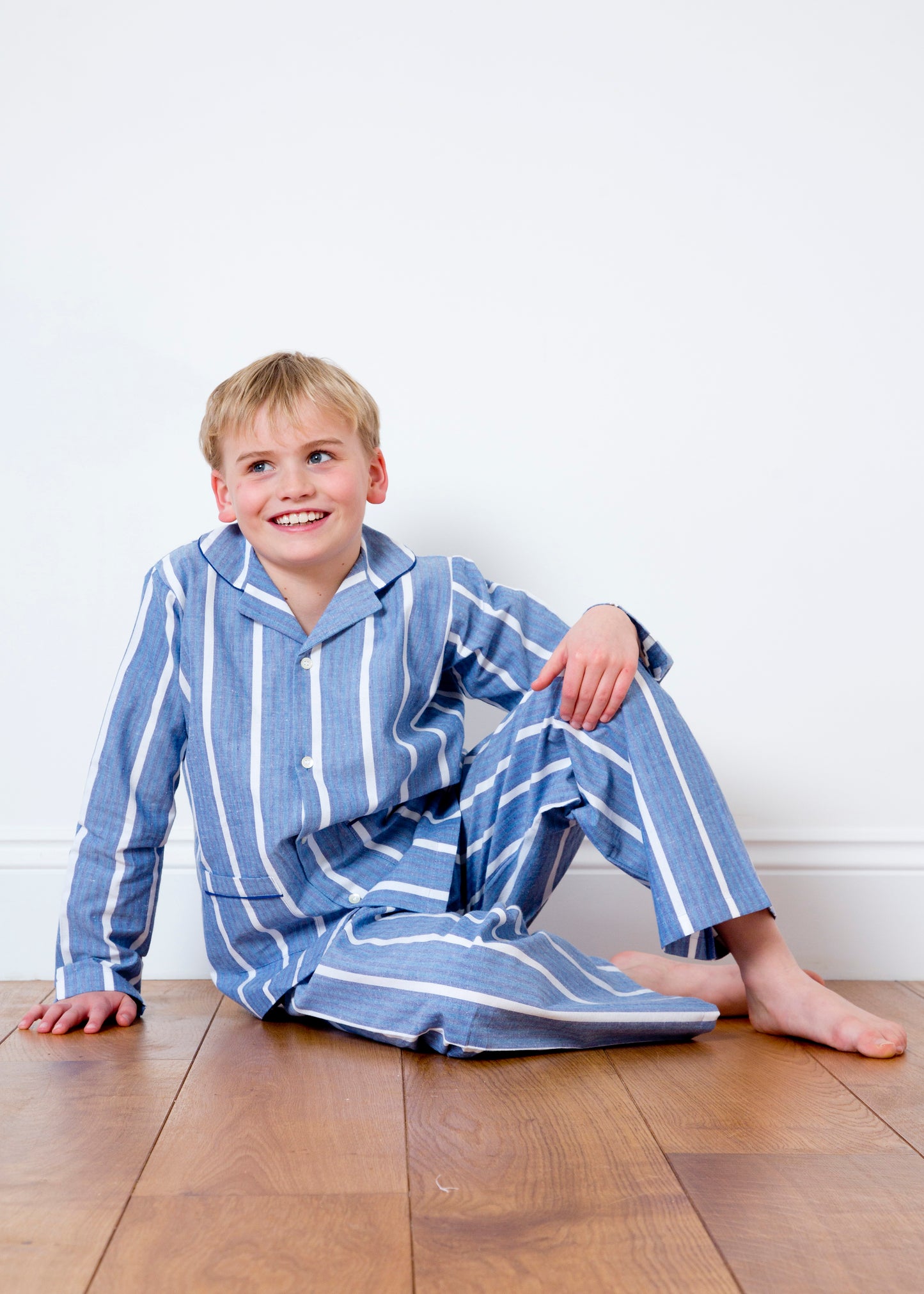 A child wearing classic cotton blue and chalk stripe pyjamas for children by TurQuaz