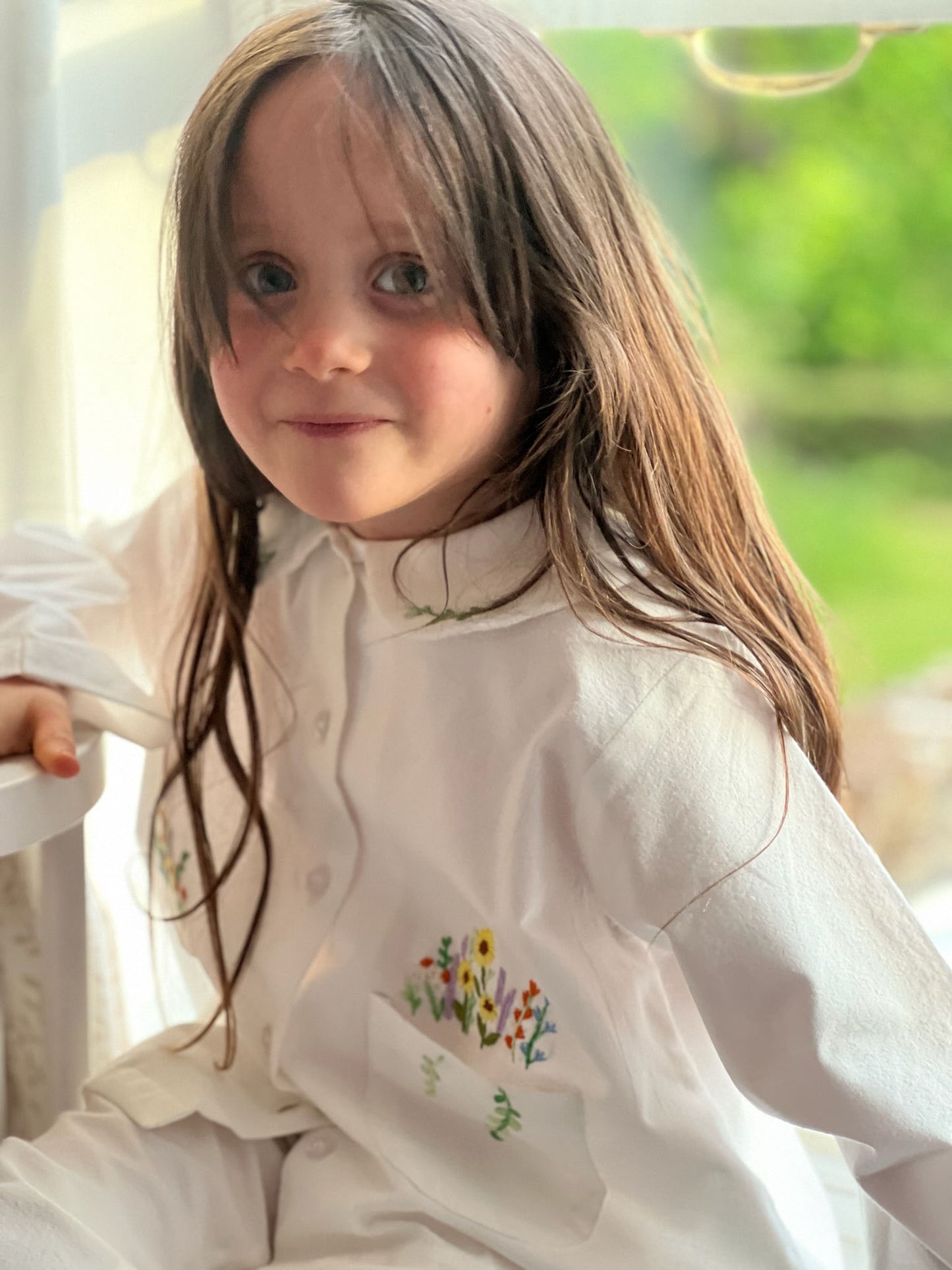 A girl wearing hand embroidered Flora cotton pyjamas by TuQuaz.