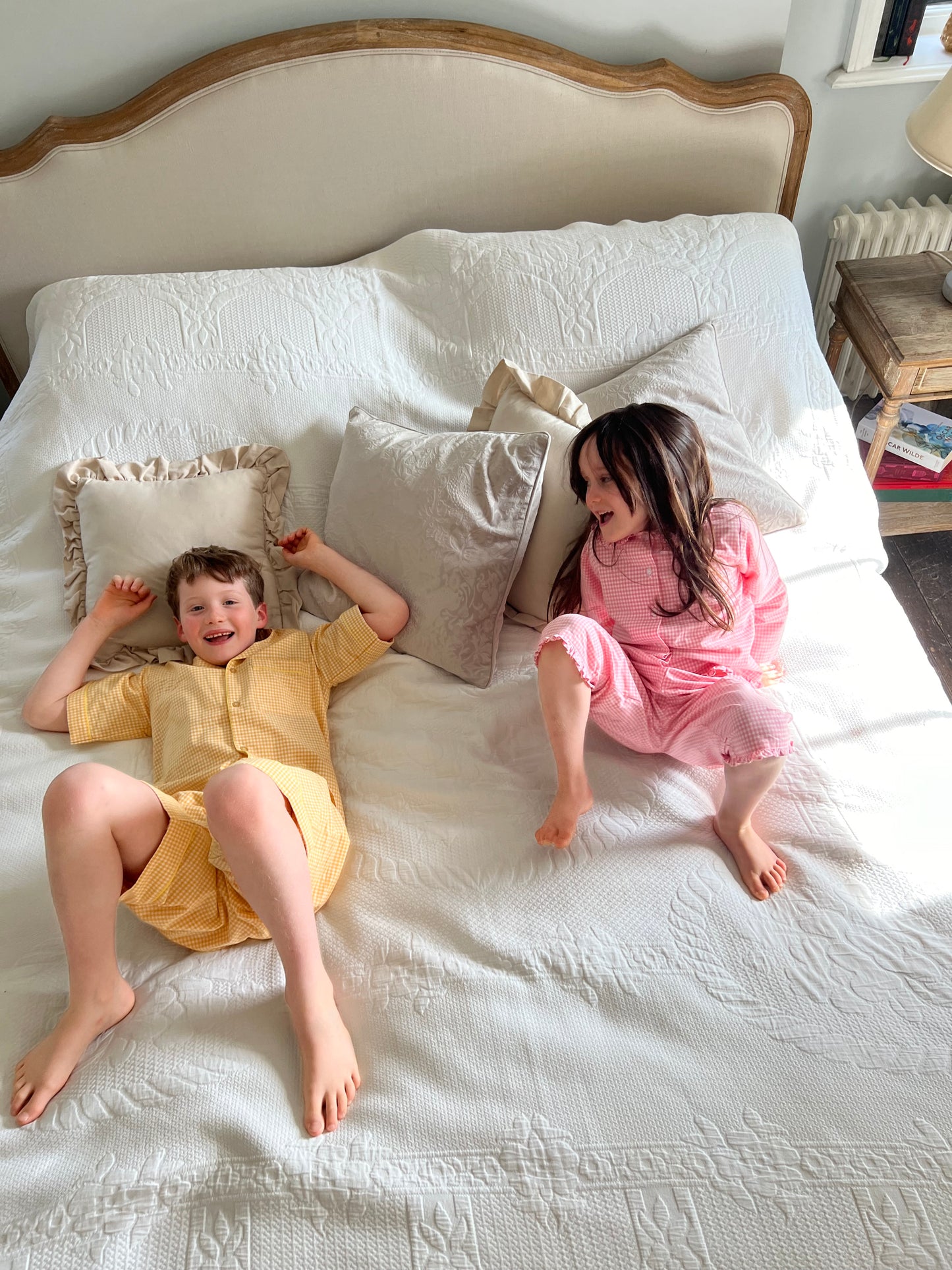 A boy and a girl wearing Sunny Day and Cotton Candy yellow and pink gingham cotton pyjamas by TurQuaz.