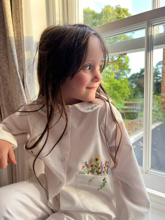 A girl looking out a window wearing Flora brushed cotton pyjamas by TurQuaz.