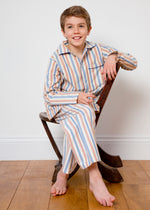 A seated boy wearing striped natural cotton Toto pyjamas by TurQuaz